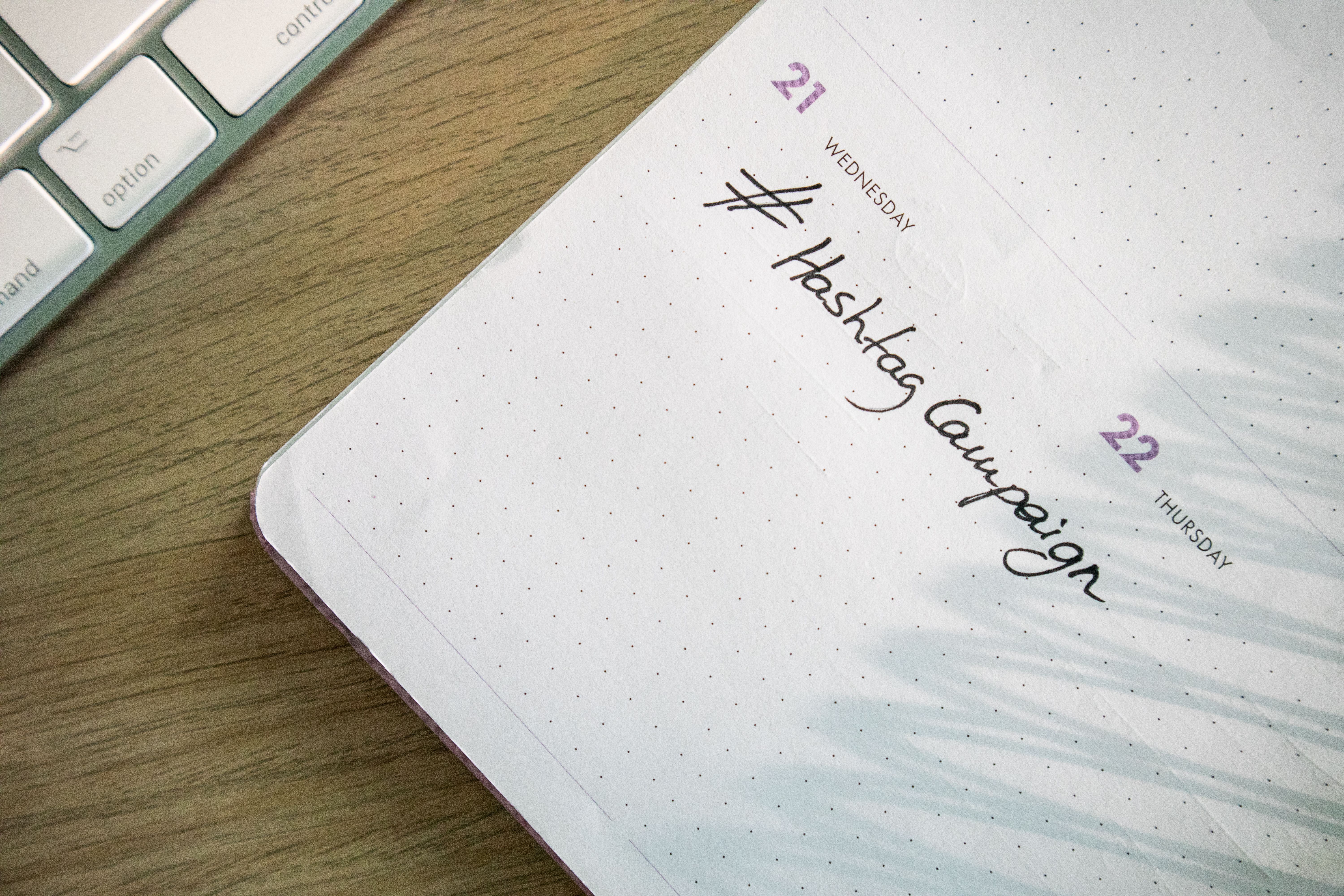 Planner labeled Hashtag Campaign beside a keyboard, illustrating social media marketing planning for authors.