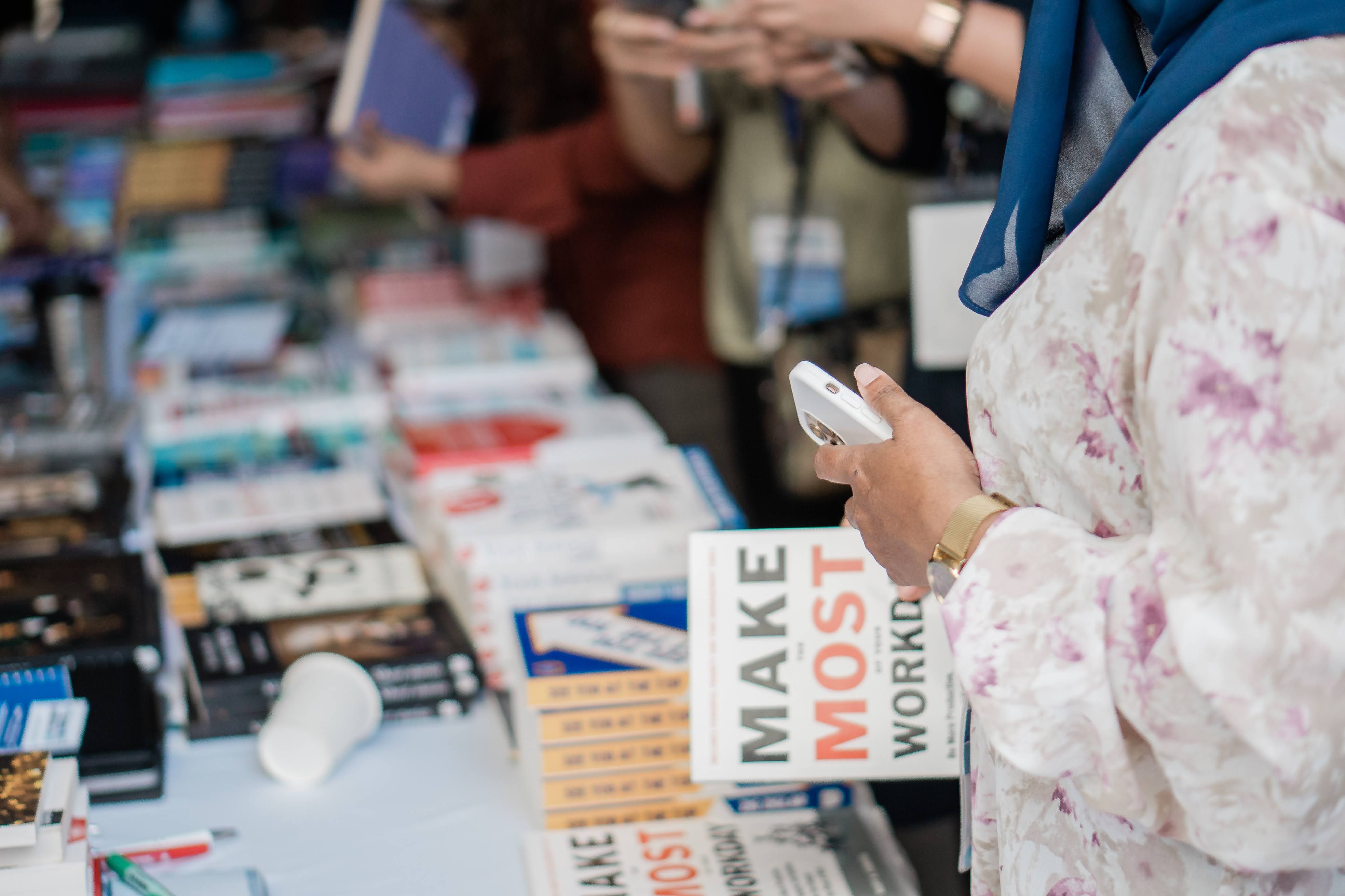 Books displayed at a book fair while visitors browse, representing independent publishing outreach and sales.