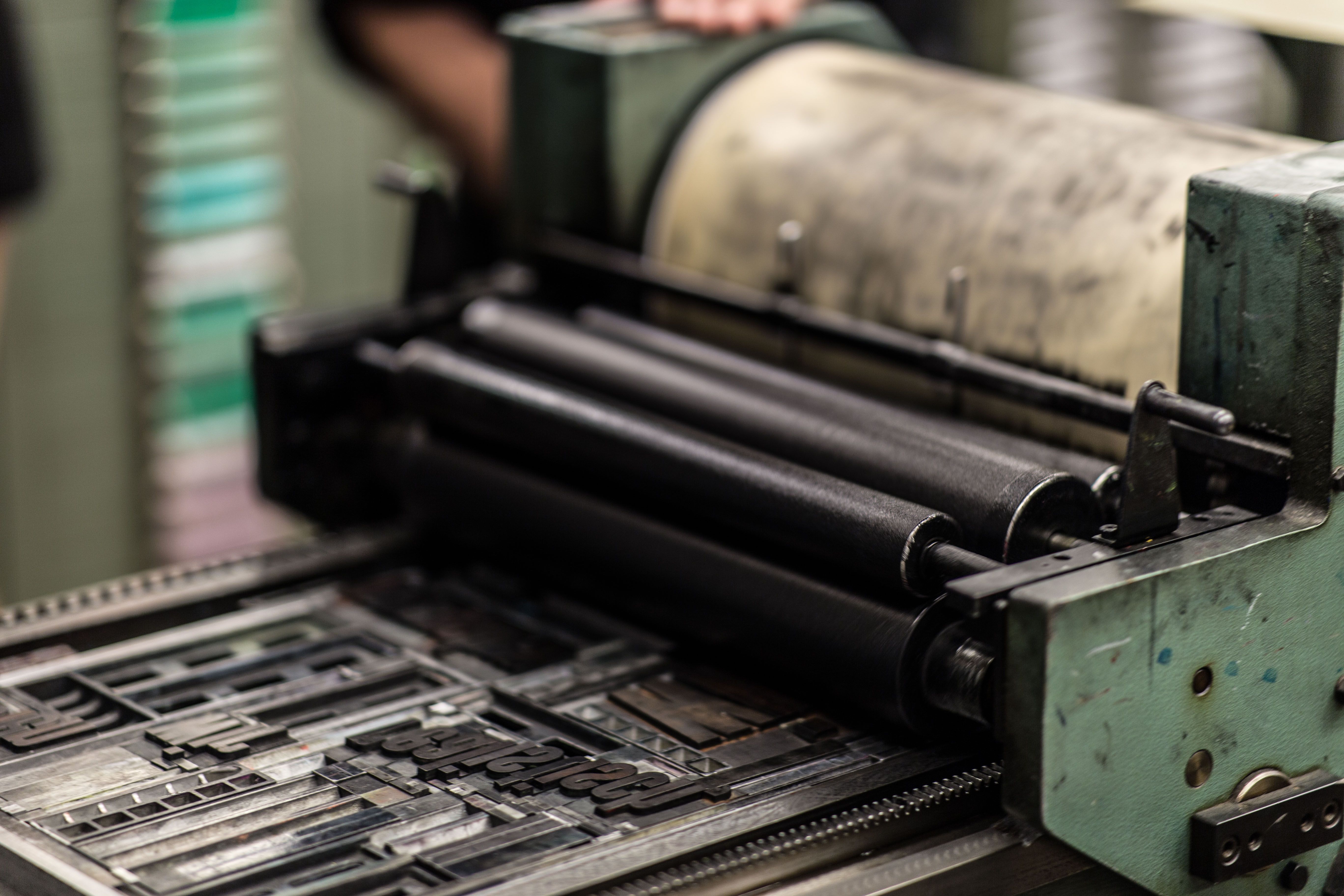 Detailed industrial printing press representing the transition from finished manuscript to printed book.